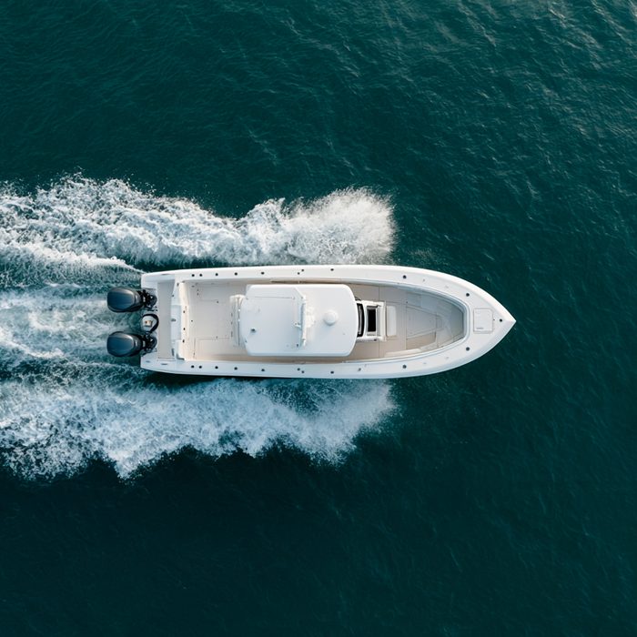 Top-down view of a powerboat with twin outboards cutting across dark water